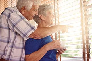 elderly couple gazing out a window at The Delaney at Georgetown senior living community