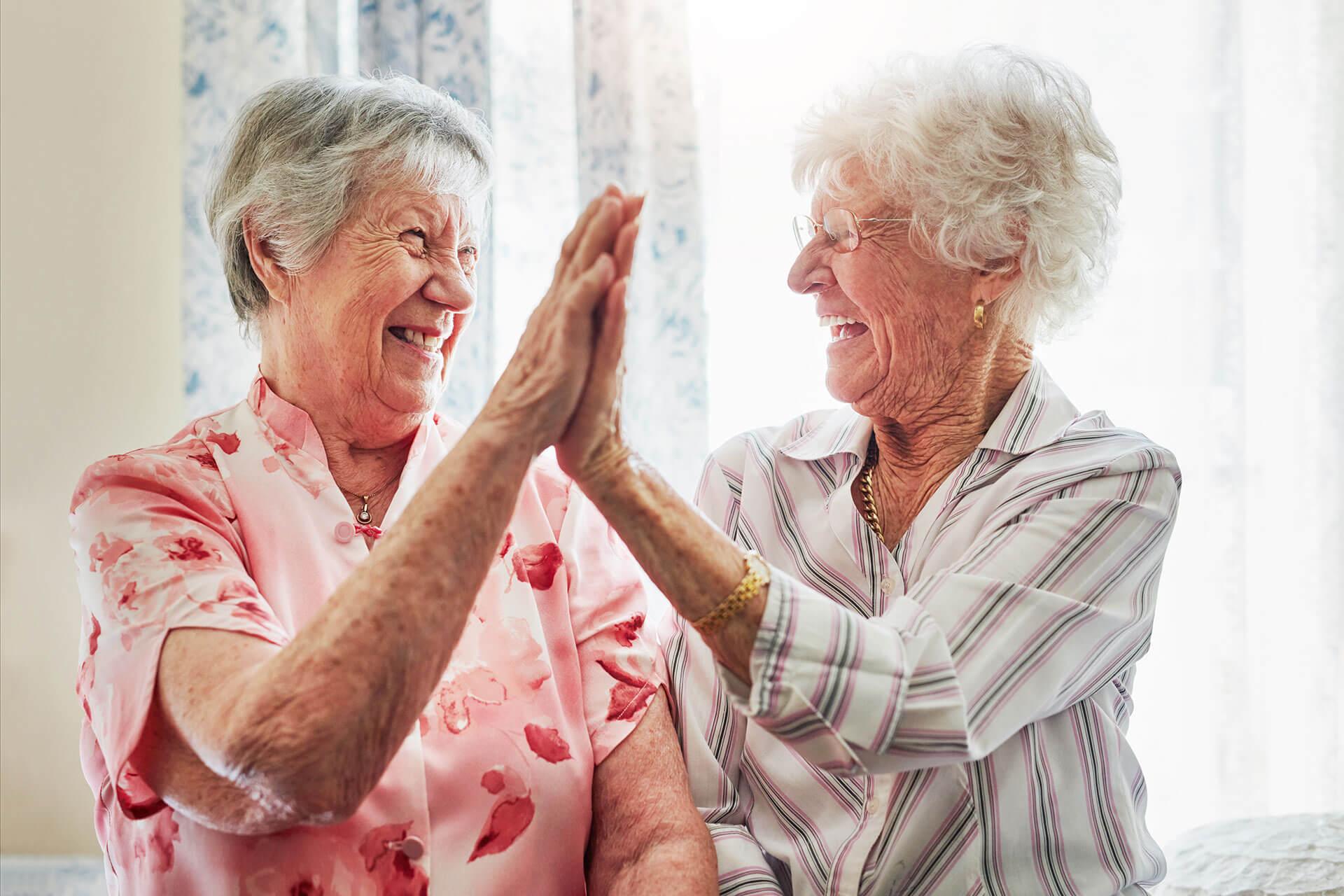 elderly women doing a high-five at The Delaney at Georgetown senior living retirement community