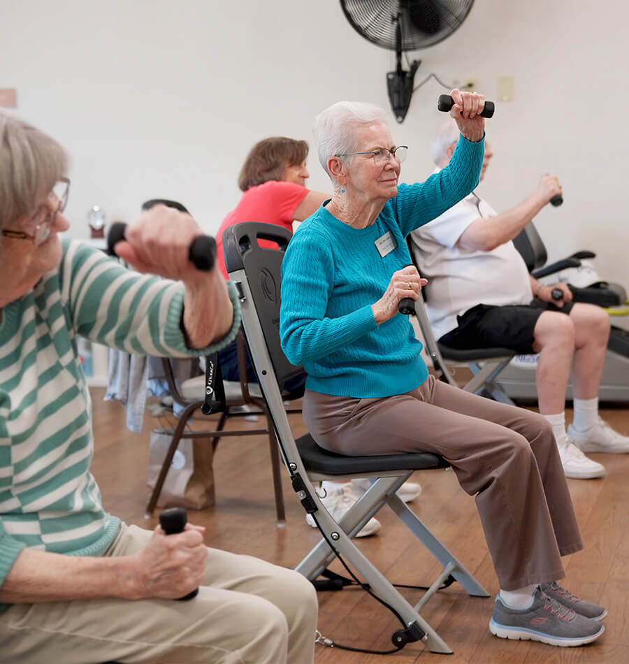 Seniors using hand weights during seated exercise class